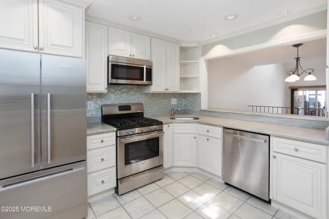 a kitchen with stainless steel appliances a sink a stove a microwave a sink a refrigerator and cabinets