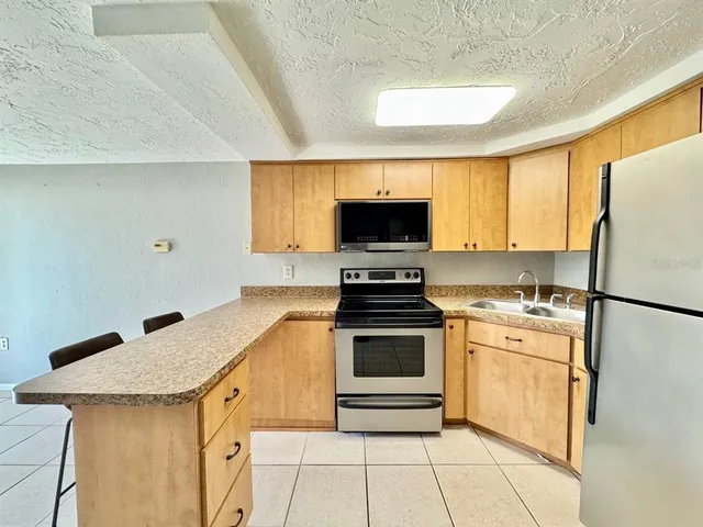 a view of a refrigerator in kitchen and an empty room