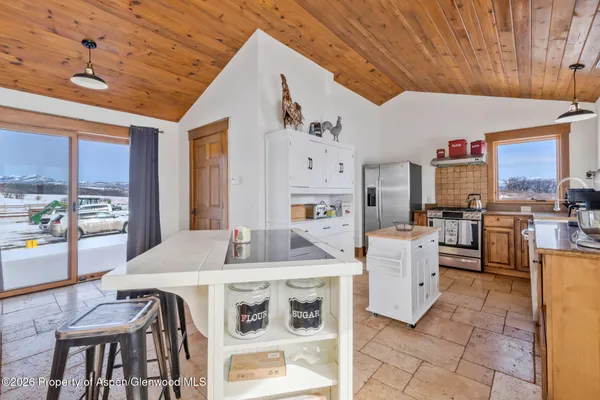 a kitchen with stainless steel appliances kitchen island granite countertop a table chairs and a refrigerator