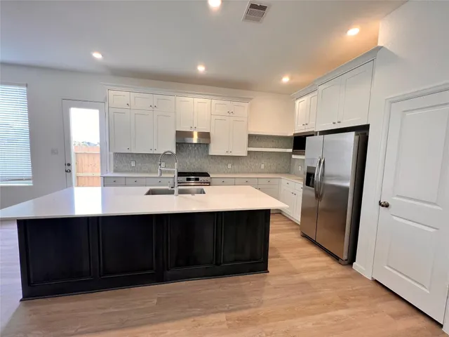 a kitchen with stainless steel appliances granite countertop a refrigerator a sink dishwasher and a stove with wooden floors
