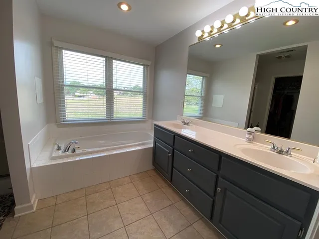 a bathroom with a tub a double vanity sink a vanity a window and a mirror