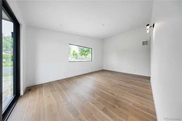 an empty room with wooden floor and windows