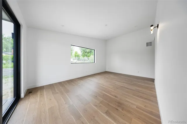 an empty room with wooden floor and windows