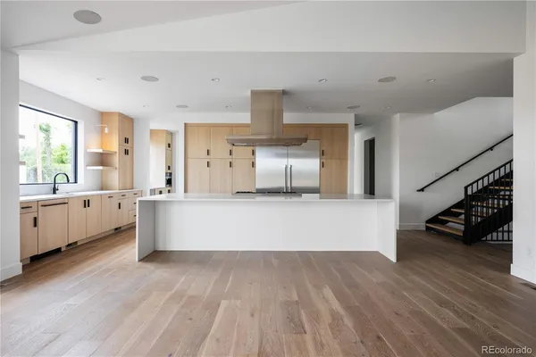 a large white kitchen with a large window and stainless steel appliances