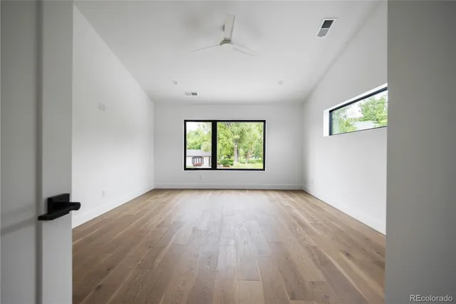 an empty room with wooden floor and windows