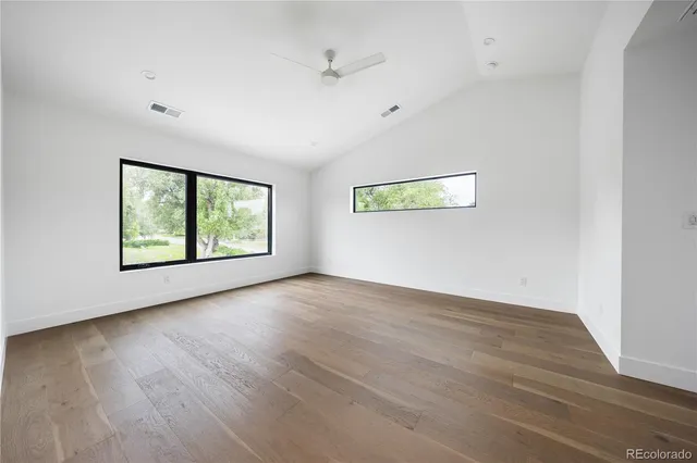 an empty room with wooden floor and windows