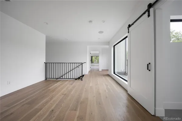 a view of a hallway with wooden floor and a bathroom