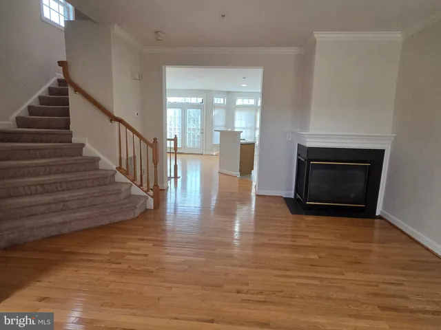 a view of an empty room with wooden floor fireplace and a window