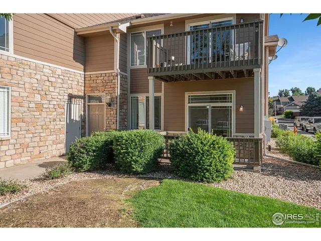 a view of a house with brick walls plants and large tree
