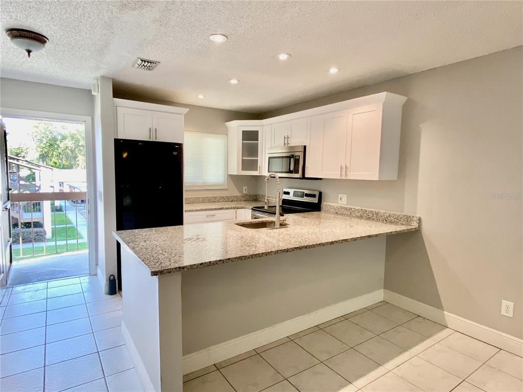 39132 County Road 54, Unit 2230 Zephyrhills, FL 33542 - Photo 4 of 17 a kitchen with kitchen island granite countertop a refrigerator a sink a stove top oven and a counter space
