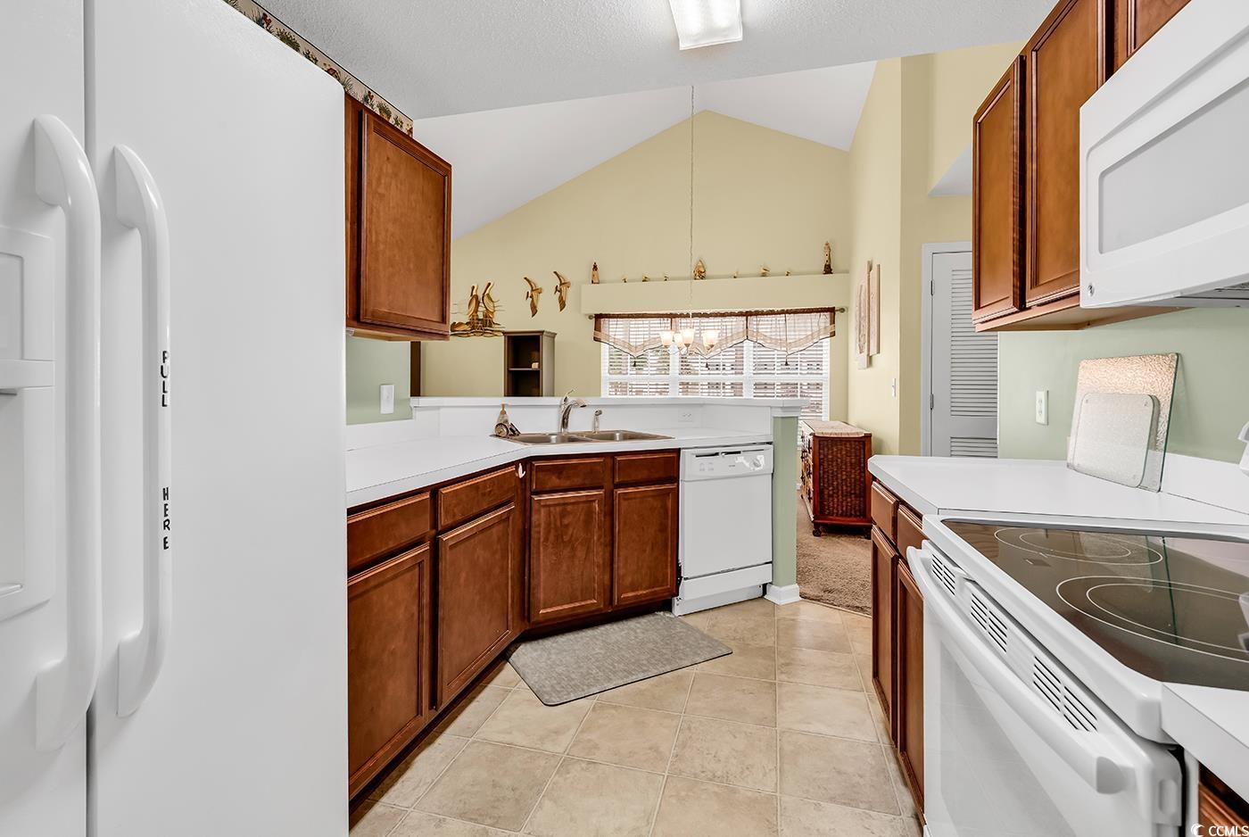 4909 Britewater Court, Unit 202 Myrtle Beach, SC 29579 - Photo 11 of 38 Kitchen featuring white appliances, light countertops, vaulted ceiling, and brown cabinetry