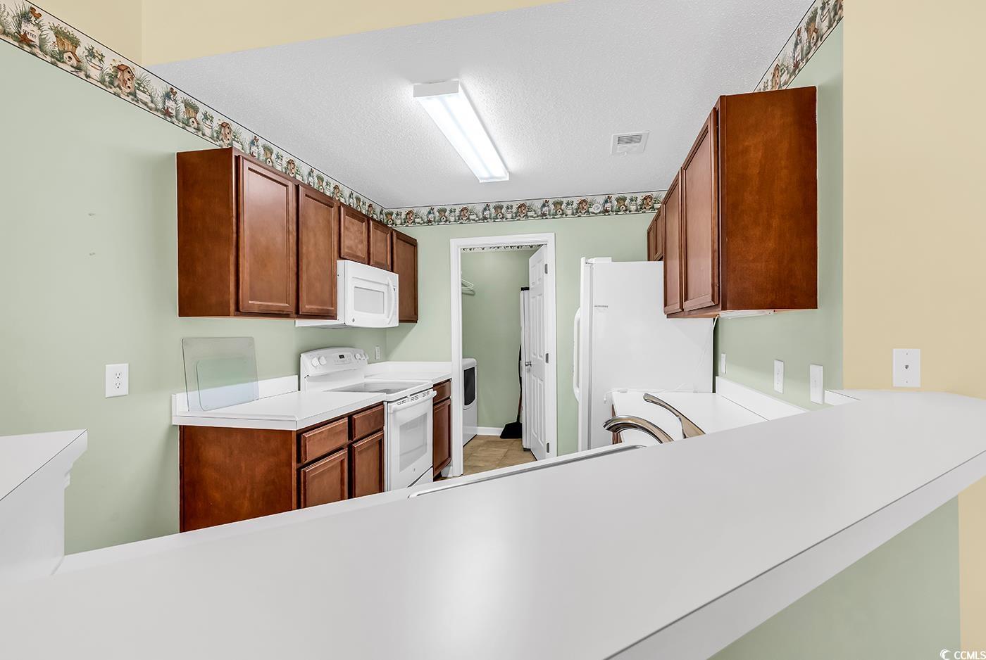 4909 Britewater Court, Unit 202 Myrtle Beach, SC 29579 - Photo 9 of 38 Kitchen with white appliances, light countertops, and brown cabinets