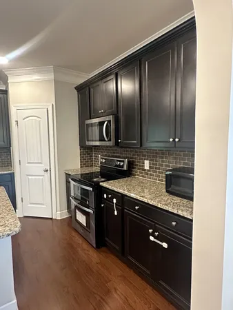 a kitchen with stainless steel appliances granite countertop a stove a sink and a refrigerator with wooden floor