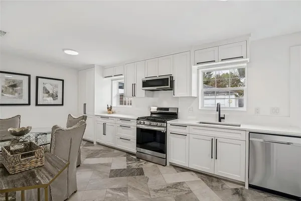 a kitchen with white cabinets and appliances
