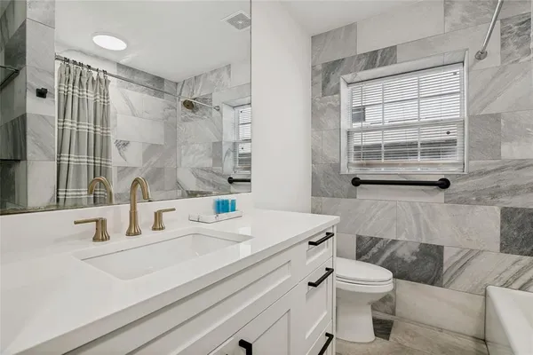 a bathroom with a sink toilet vanity and tub