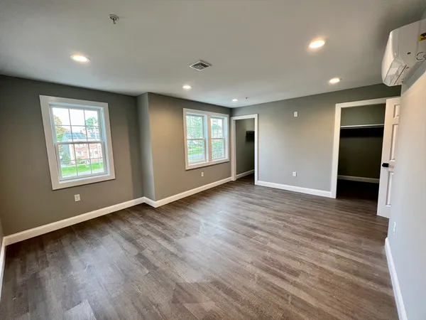 an empty room with wooden floor and windows
