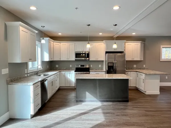 a large kitchen with stainless steel appliances granite countertop a stove a sink dishwasher and a microwave oven with wooden floor