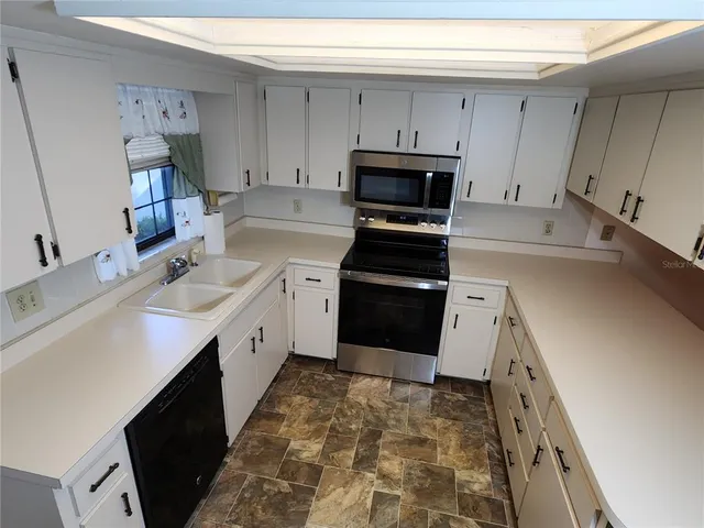 a kitchen with granite countertop a sink stove and cabinets
