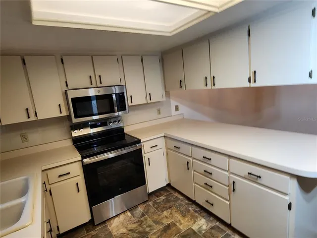 a kitchen with granite countertop white cabinets and black appliances