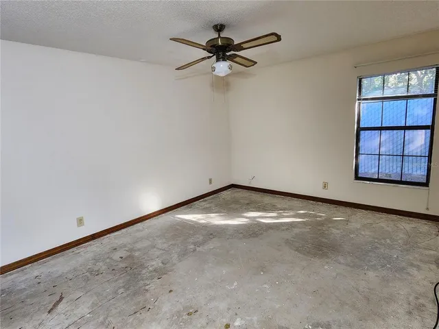 an empty room with windows and ceiling fan