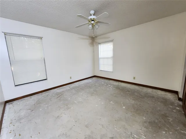 an empty room with windows and fan