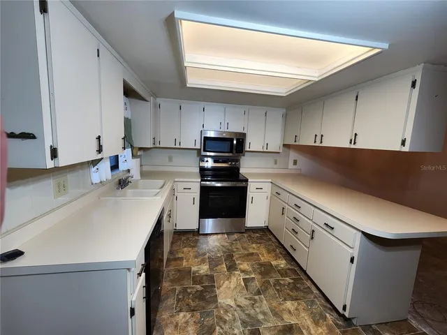 a kitchen with granite countertop white cabinets and white appliances