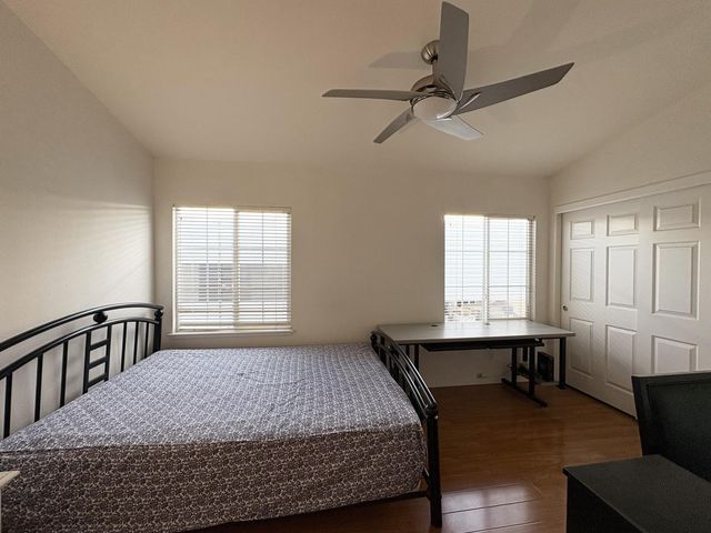 a bedroom with a bed a table and windows