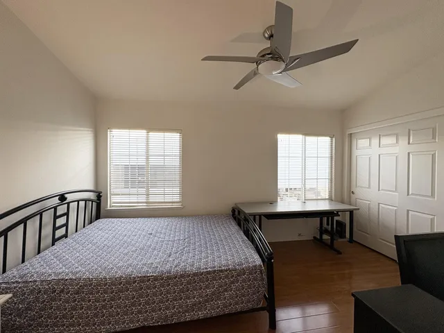 a bedroom with a bed a table and windows