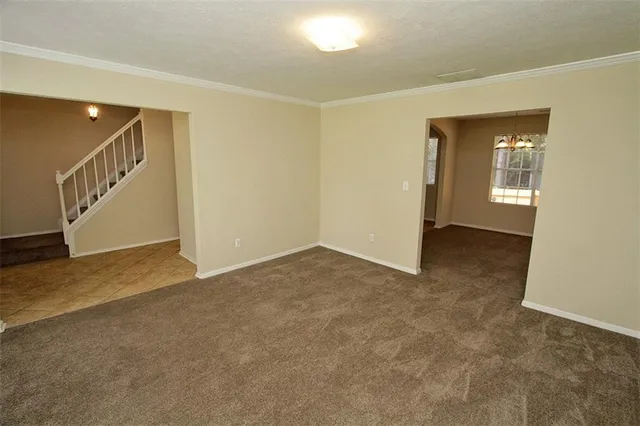 a view of an empty room with wooden floor and a bathroom