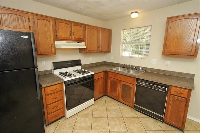 a kitchen with granite countertop a refrigerator and a stove top oven