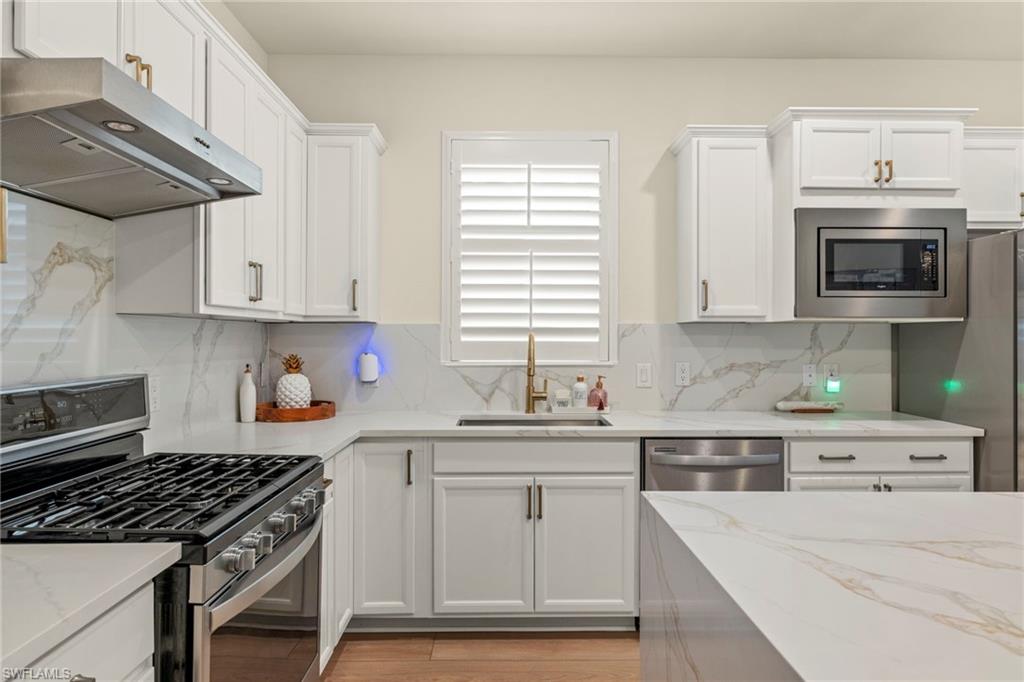 2170 Yellowfin Circle Naples, FL 34114 - Photo 5 of 26 a kitchen with stainless steel appliances a sink dishwasher stove and white cabinets