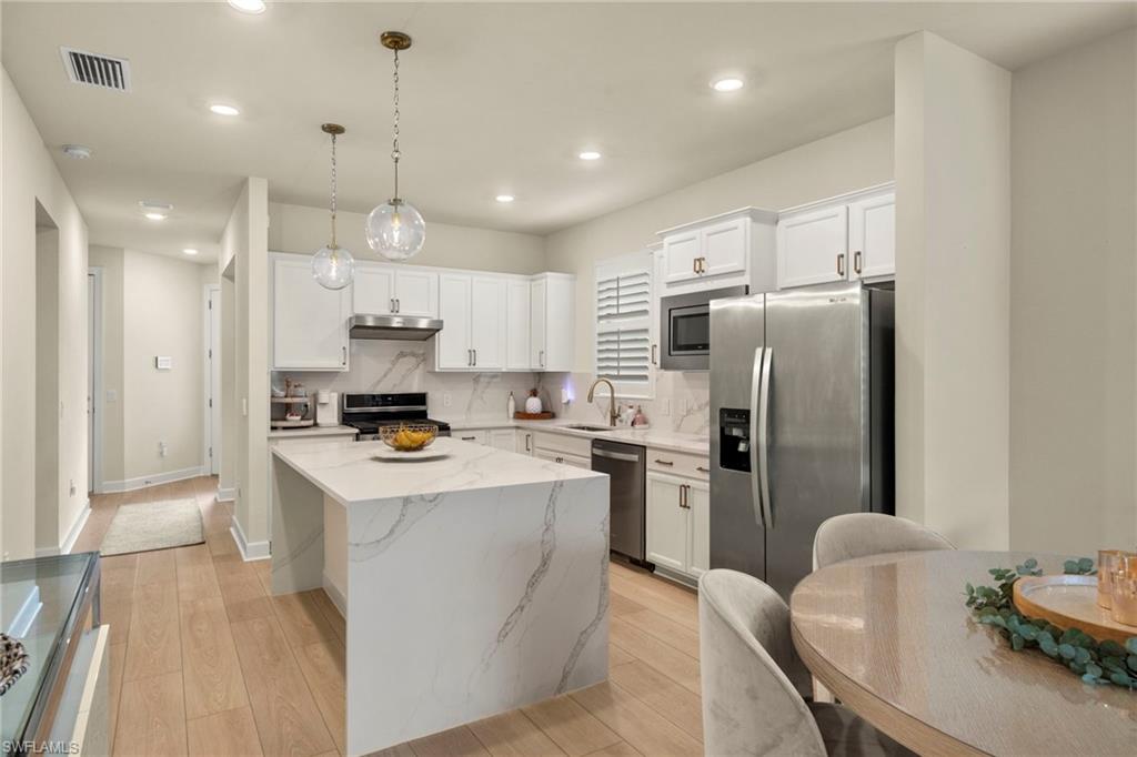 2170 Yellowfin Circle Naples, FL 34114 - Photo 7 of 26 a kitchen with stainless steel appliances a refrigerator a stove a sink a dining table and chairs