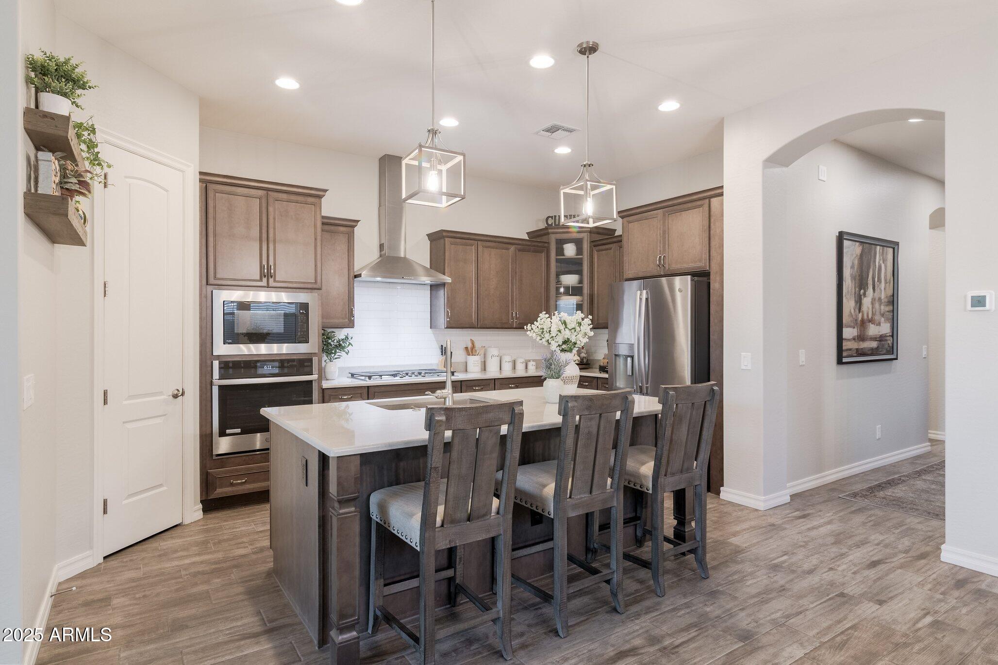 3437 East Appaloosa Road Gilbert, AZ 85296 - Photo 12 of 47 a kitchen with kitchen island a refrigerator and a dining table