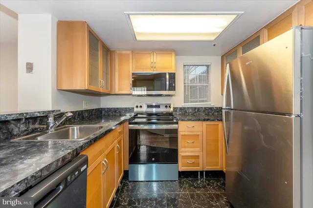 a kitchen with stainless steel appliances granite countertop a stove a refrigerator and a sink