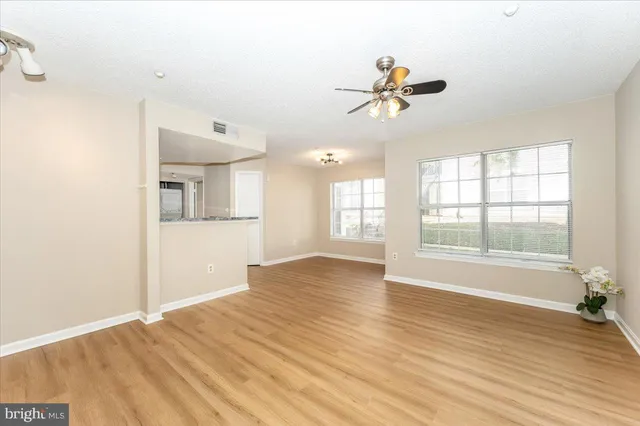 a view of empty room with wooden floor and fan