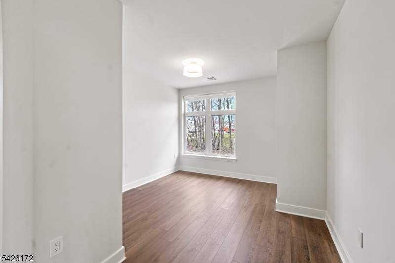 434 Springfield Avenue, Unit 146 Berkeley Heights, NJ 07922 - Photo 28 of 32 an empty room with wooden floor and windows