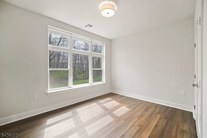 434 Springfield Avenue, Unit 146 Berkeley Heights, NJ 07922 - Photo 30 of 32 an empty room with wooden floor and windows