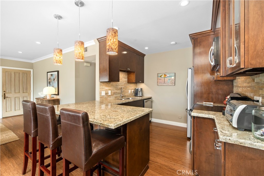 33623 Avenida Capri, Unit 60 Dana Point, CA 92629 - Photo 7 of 38 a kitchen with granite countertop a table chairs stove and refrigerator