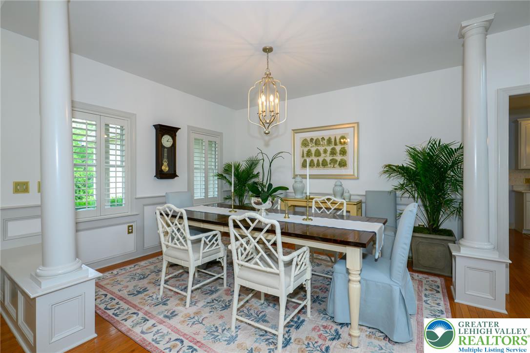 217 Gower Road Nazareth, PA 18064 - Photo 10 of 44 Ornate columns frame a formal dining room with a captivating chandelier and polished hardwood flooring.