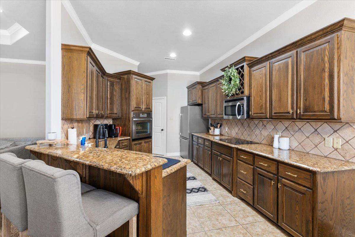 9804 Juneau Avenue Lubbock, TX 79424 - Photo 11 of 30 a kitchen with kitchen island granite countertop a sink stove and cabinets