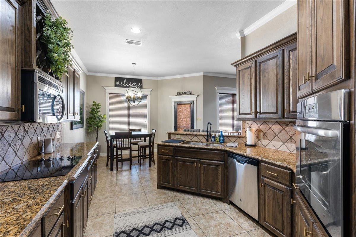 9804 Juneau Avenue Lubbock, TX 79424 - Photo 12 of 30 a kitchen with stainless steel appliances granite countertop a sink stove and cabinets