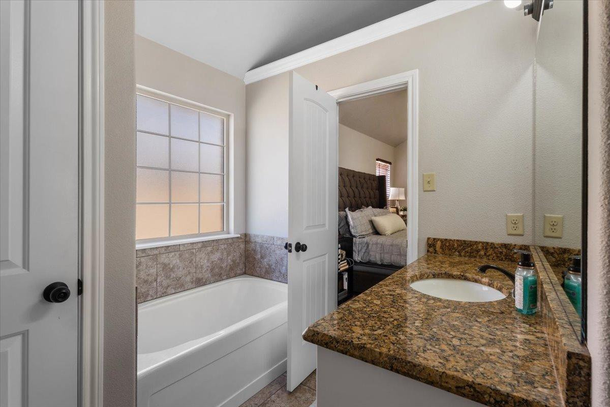 9804 Juneau Avenue Lubbock, TX 79424 - Photo 17 of 30 a bathroom with a granite countertop sink and a bathtub