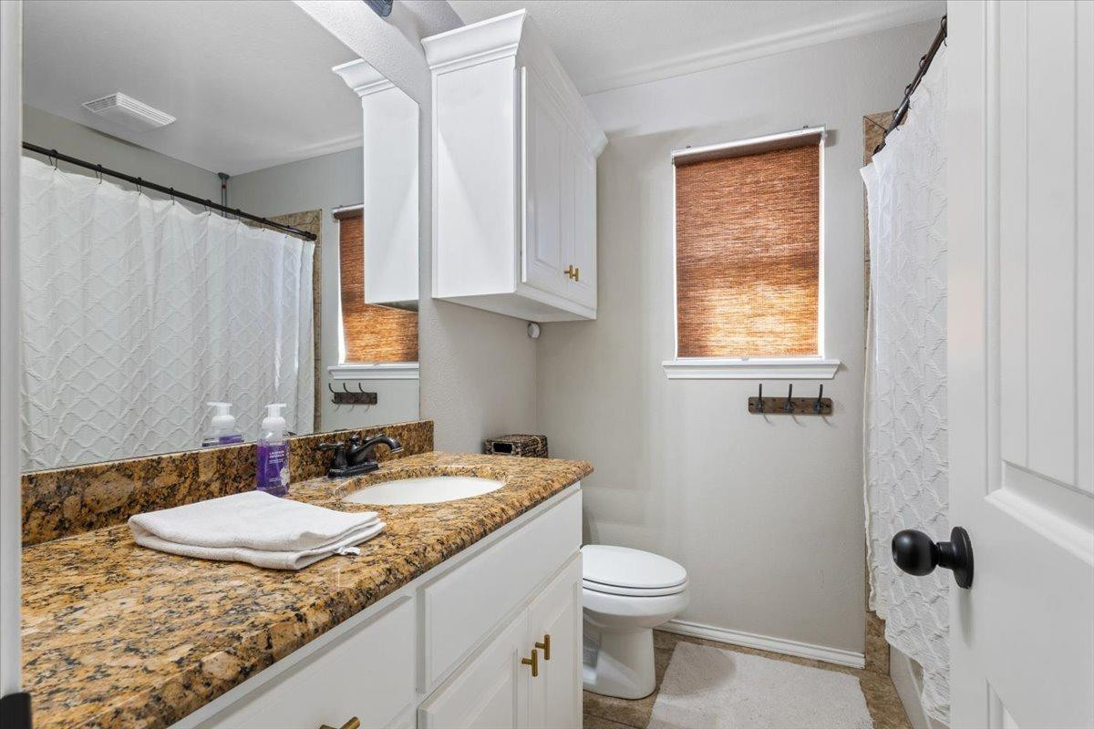 9804 Juneau Avenue Lubbock, TX 79424 - Photo 21 of 30 a bathroom with a granite countertop sink toilet and mirror