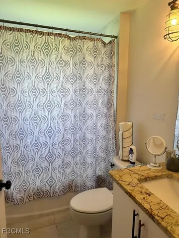 a bathroom with a granite countertop toilet and a sink