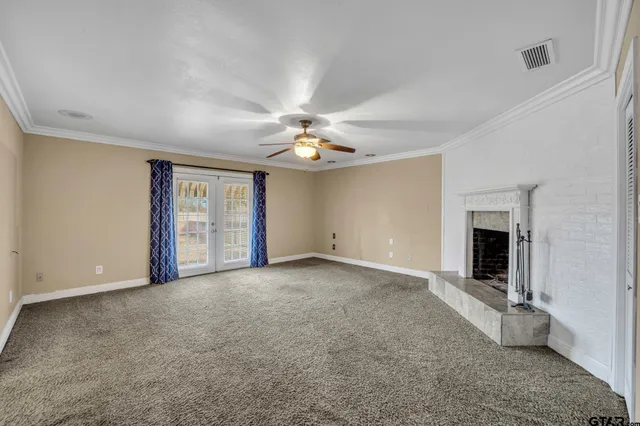 a view of an empty room with a fireplace and a chandelier fan