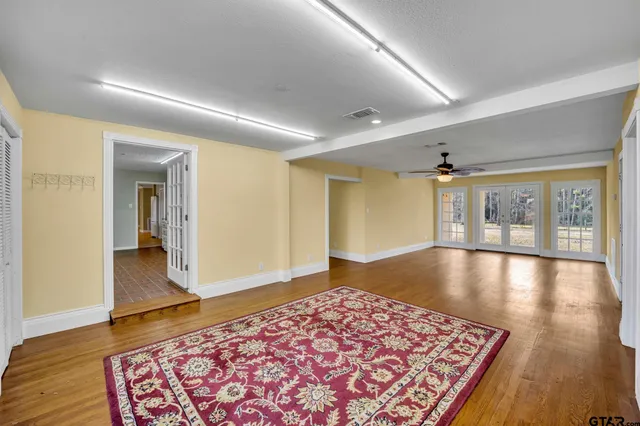 an empty room with wooden floor chandelier and windows