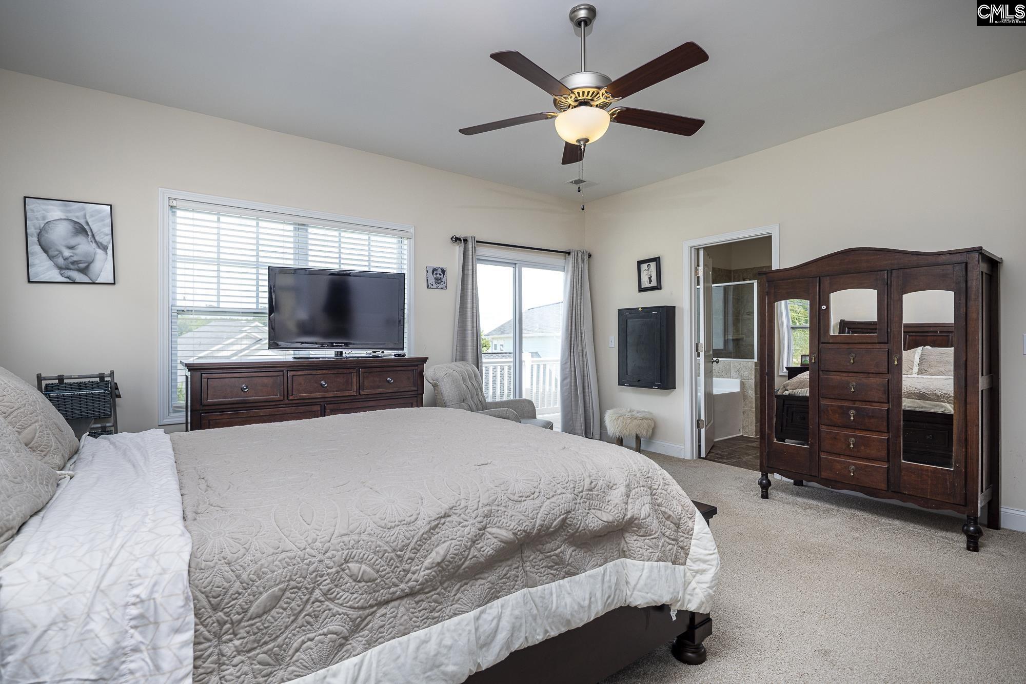 213 Sunset Point Drive Lexington, SC 29072 - Photo 19 of 35 a bedroom with a large bed a flat tv screen and a chandelier