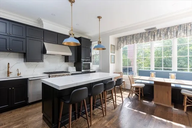 a kitchen with stainless steel appliances granite countertop a sink a stove and a wooden floor