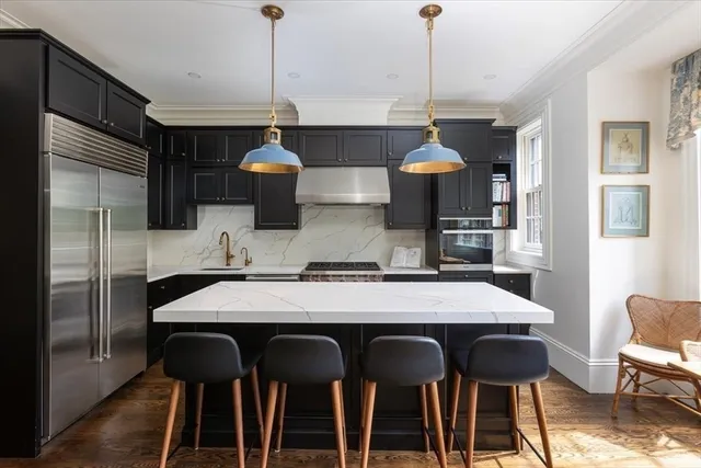 a kitchen with stainless steel appliances granite countertop a dining table chairs and white cabinets
