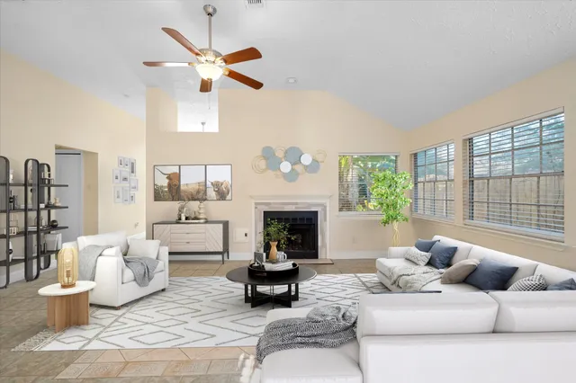 an empty room with windows fireplace and fan